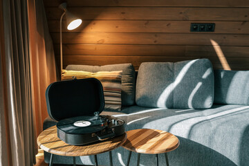 Turntable on a wooden coffee table in a cozy living room with soft lighting, striped pillow on a...