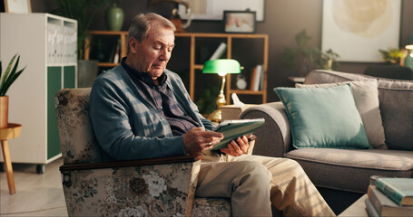 Home, senior man and tablet on sofa for reading online news, retirement ebook or gambling website. Relax, elderly person or digital app in living room for web surfing, playing bingo game or streaming