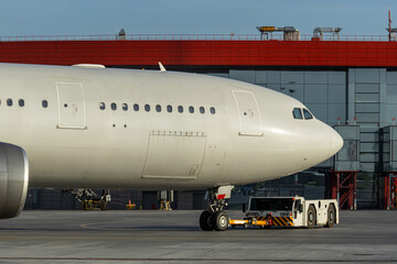 The tractor is towing the wide body passenger airplane