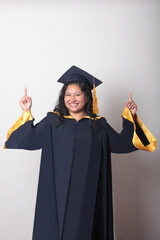 Young brunette Latina woman wearing a cap and gown celebrates her graduation and the completion of...