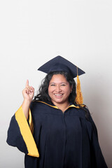 Young brunette Latina woman wearing a cap and gown celebrates her graduation and the completion of...