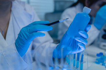 a female chemist is testing various liquid compounds in a lab, a scientist is doing research on the...