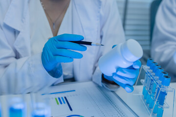 a female chemist is testing various liquid compounds in a lab, a scientist is doing research on the...