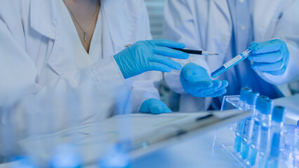 two scientists consult each other while conducting an experiment on a liquid substance in a...