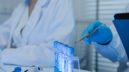 two scientists consult each other while conducting an experiment on a liquid substance in a...