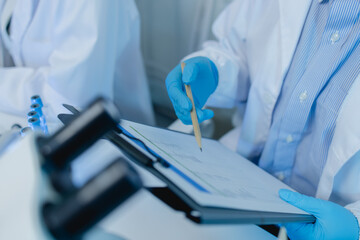 two scientists consult each other while conducting an experiment on a liquid substance in a...