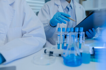 two scientists consult each other while conducting an experiment on a liquid substance in a...