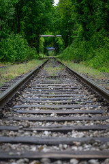 Railway tracks and sleepers with trees in the background and a bridge, captured in natural outdoor...