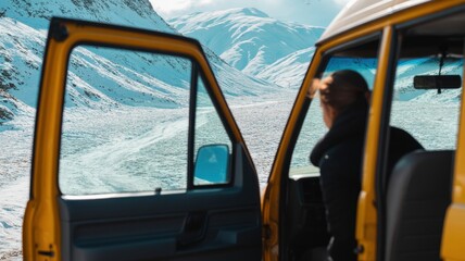 Female adventurer enjoying mountain view from yellow van in winter landscape