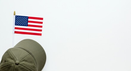 A flat lay composition of a military-style veteran cap placed beside a carefully laid small U.S. flag on a white background.