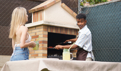 Two friends are grilling meat and enjoying refreshing drinks at a backyard barbecue