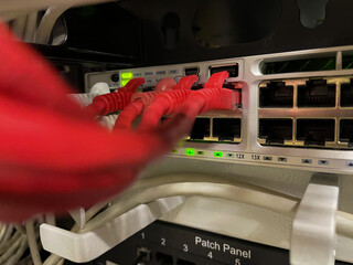 Several network wires connect to switching hub. Utp wires are in the office router close-up. Ethernet cables connected to the switch. Blurred foreground, focus on background