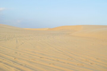 Sweeping Sand Dunes Landscape with Tire Tracks Under a Clear Blue Sky. Mui Ne, Vietnam, White Dunes.