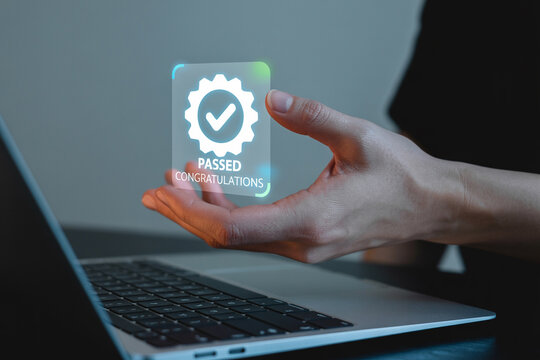 Hand holding a holographic passed certificate above a laptop computer with congratulations message