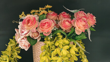 Elegant plastic flower arrangement featuring roses and yellow flowers against a dark background