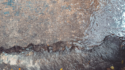 Iridescent stream on rocky terrain creates a textured natural abstraction reflecting sky