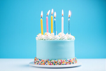 blue birthday cake with six lit candles on top