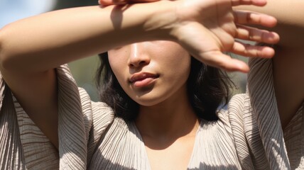 Fototapeta premium Asian young adult female posing outdoors in sunlight with arm shadow effects