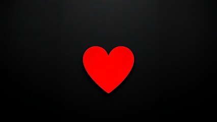 A red heart shape stands out against a textured black background with warm lighting.