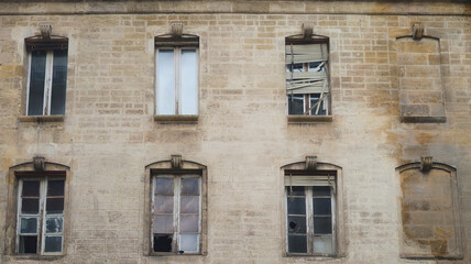 derelict building facade illegally squatted and dilapidated and a broken window shutter upstairs
