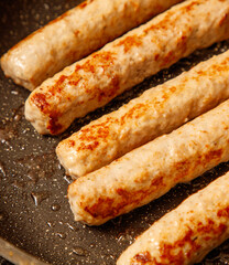 A pan of sizzling sausages with a black background