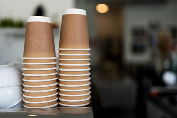 Stacks upside down empty brown takeaway disposable coffee cardboard cups on the coffee machine in the cafe