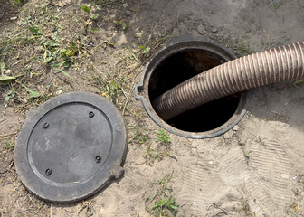 A black pipe is being used to drain a hole in the ground