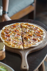 Pepperoni pizza on wooden serving board on the table