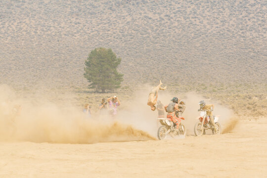 Motocross rider performing backflip stunt in desert race