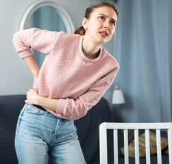 Young woman suffering from lower back pain at home