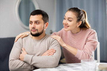 Tender loving young woman comforting distressed offended husband after spat while sitting together...