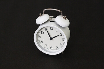 White Circular Alarm Clock on Black Background Captured in Close-Up Perspective