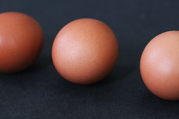 Three Brown Eggs with Smooth Shells on a Dark Background