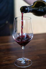 A man is pouring red wine in the glass