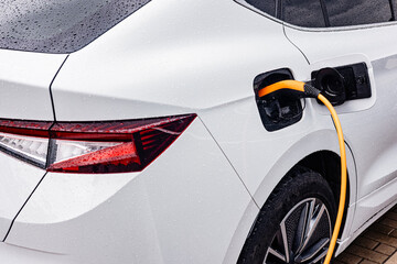 Electric car being charged in the rain