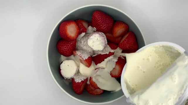 Strawberries in Bowl with Cream being poured over them