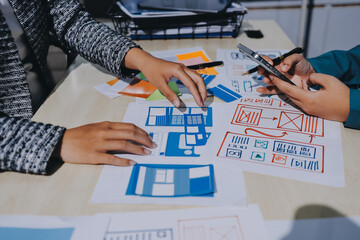 Group of young application developers analyzing uxui mobile app templates during a working meeting