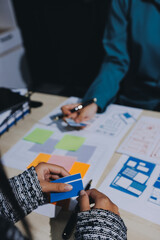 Group of young application developers analyzing uxui mobile app templates during a working meeting