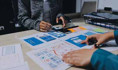 Group of young application developers analyzing uxui mobile app templates during a working meeting