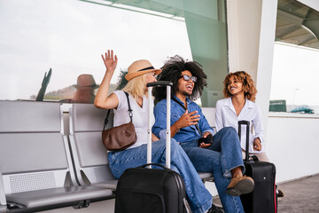 Group of multi ethnic friends waving goodbye while sitting and chatting in the waiting area of an...