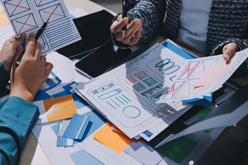 Group of young application developers analyzing uxui mobile app templates during a working meeting