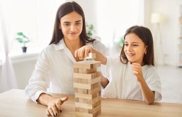 Happy friendly mother and daughter active family at home enjoy playing jenga board game together,...
