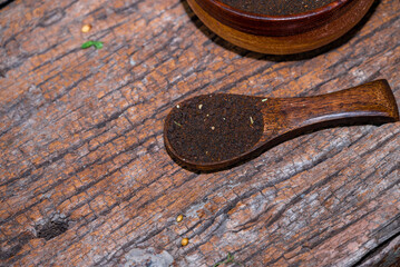 indian black tea, teaspoon with tea leaves on wooden table. Black tea powder in a wooden...