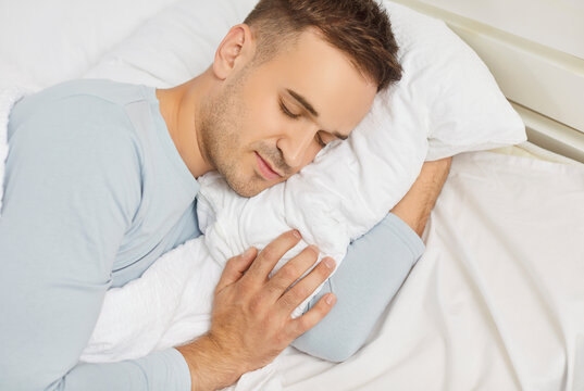 Close up of peaceful relaxed man sleeping in sweet dreams lying on bed in cozy modern white bedroom in the morning. Healthy young guy napping with comfort resting on pillow at home. - Powered by Adobe