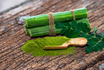 Moringa leaves in wooden bowl with Moringa powder on wooden background
