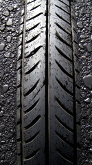 Fototapeta premium Close-up view of a car tire's tread. Wet asphalt road with small pebbles.