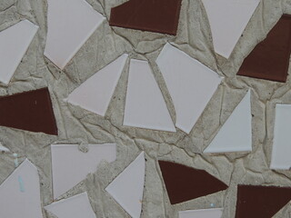 triangles of colored ceramics in cement mortar in wall texture as design element, close-up of triangle shaped ceramic tiles in concrete base as abstract texture