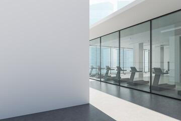 Modern gym interior with treadmills inside glass-walled fitness center in high-rise city building...