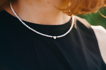 Close-up of Elegant Pearl Bead Necklace with Heart Pendant on Black Dress