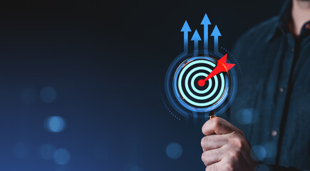 Businessman holding dartboard with red arrow hitting bullseye, symbolizing strategy and success on...